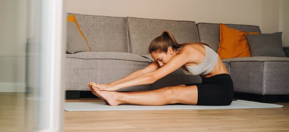 Woman in activewear stretching on yoga mat at home, promoting a healthy lifestyle.